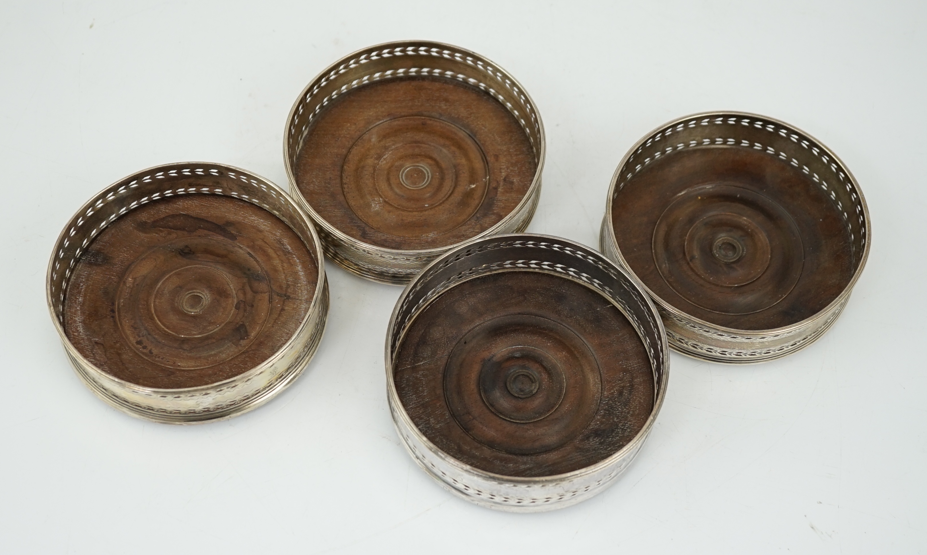 A set of four George III pierced silver mounted wine coasters, John Younge & Co